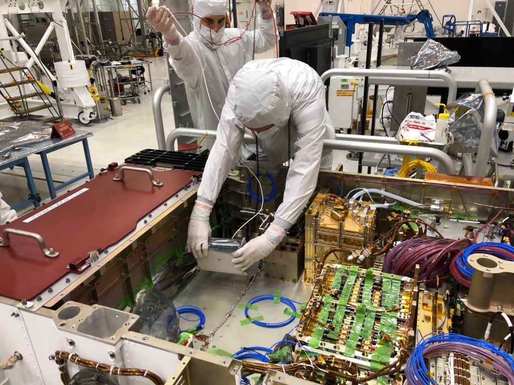 Technicians installing the Mastcam-Z Digital Electronics Assembly (DEA) into the body of the Mars 2020 mission’s Perseverance rover at JPL in April, 2019.